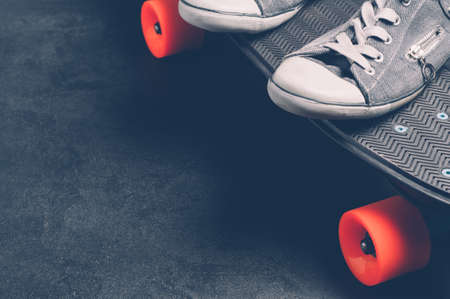 Skateboard and sneakers on a dark background