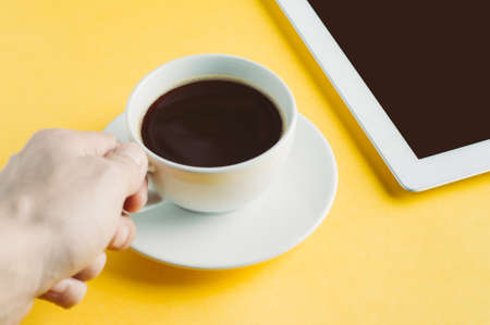 Tablet PC and coffee Cup on yellow backgroundの写真素材