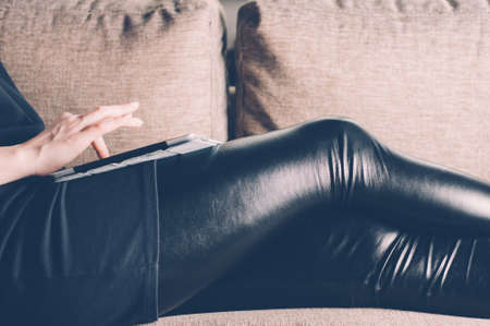 Woman sitting on sofa and using tablet pcの写真素材