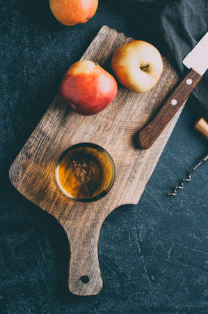 Apple cider in a glass and fresh apples on dark stone background. Vertical croppingの写真素材