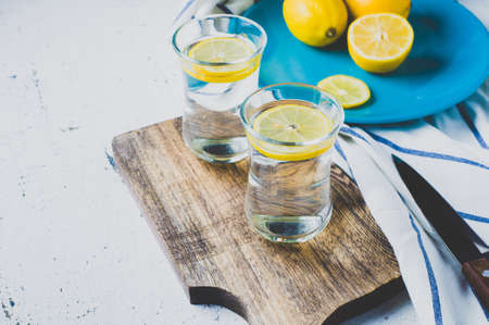 Water with lemon in the glass and fresh lemons on bright background. Diet or weight loss conceptの写真素材