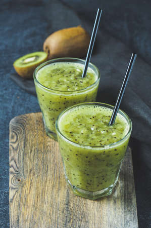 Fresh kiwi juice in glass over dark background. Diet concept, healthy eating or weight loss. Space for text, vertical croppingの写真素材