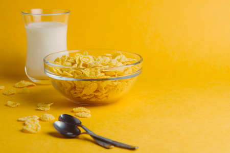 Corn flakes and milk on a yellow background. Breakfast concept