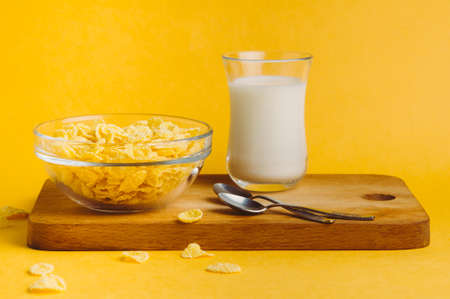 Corn flakes and milk on a yellow background. Breakfast concept