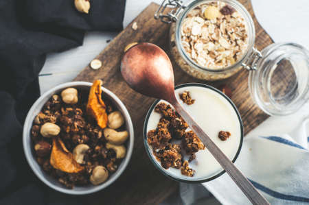 Yoghurt, muesli, nuts and dried fruits on a wooden Board over dark stone background. Diet, weight loss or healthy eating concept. Copy space for text or designの写真素材