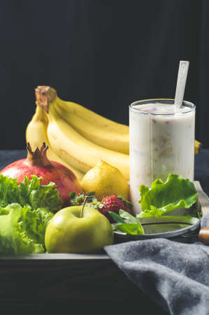 Fresh fruit and milkshake in a wooden box over dark concrete backgroundの写真素材