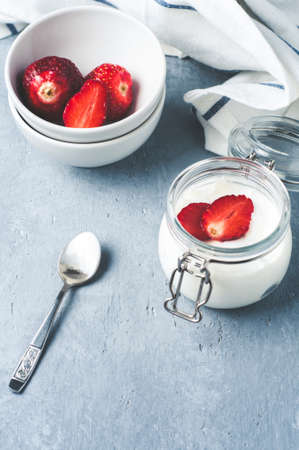 Strawberry yogurt and berry in jars on a gray concrete backgroundの写真素材