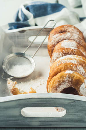 Homemade donuts with powdered sugar in a white wooden boxの写真素材