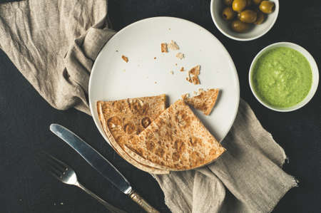 Olives, sauce and homemade scones on a white ceramic plate over dark concrete background