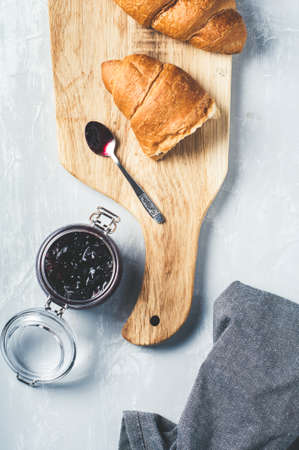 Fresh croissants with jam and jar of jam on a grey concrete background. Breakfast concept, top viewの写真素材