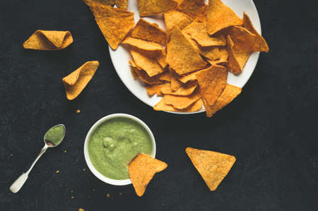 Mexican corn chips and fresh sauce on dark concrete backgroundの写真素材
