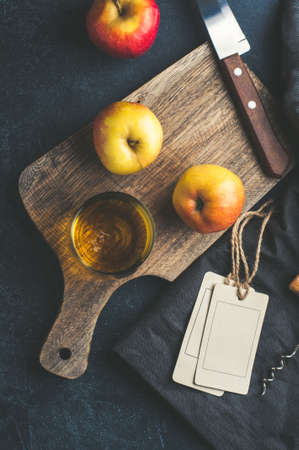 Apple cider in a glass and fresh apples on dark stone background. Vertical croppingの写真素材