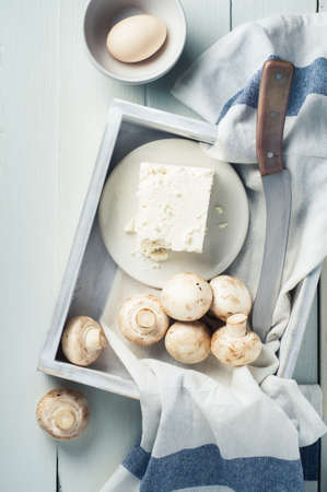 Mushrooms, cheese and eggs in a white wooden box on a white backgroundの写真素材