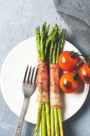 Asparagus with ham egg and tomatoes on blue plate