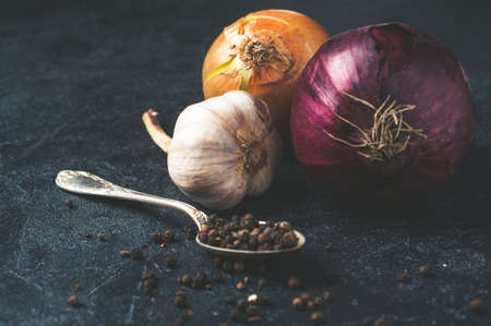 Onion, garlic, pepper and other spices on dark concrete backgroundの写真素材