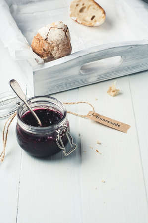 Homemade jam in a jar and bread in a white wooden box over white wooden backgroundの写真素材