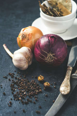 Onion, garlic, pepper and other spices on dark concrete backgroundの写真素材