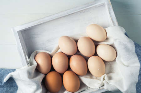 Chicken eggs in a white wooden box on a white background