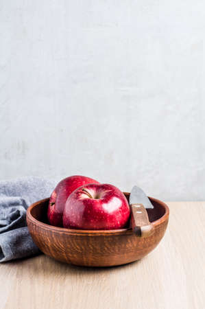 Red apples in a bowl on a light wooden background. Diet or healthy eating conceptの写真素材