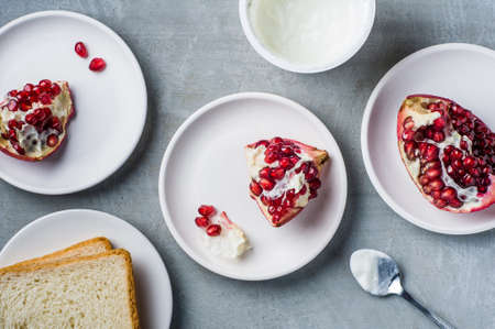 Pomegranate in the bowl and the yogurt in a Cup over gray concrete backgroundの写真素材