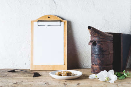 Flowers, smoker and tools on a wooden table against the background of a light wall. Concept of an apiaryの写真素材