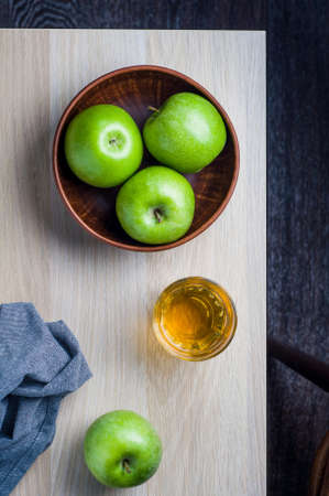 Green apples in a bowl on a light wooden background. Diet or healthy eating conceptの写真素材