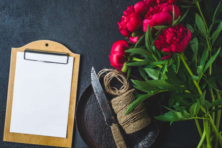 Bouquet of red peonies and tablet on a dark concrete backgroundの写真素材