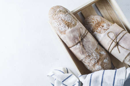 Homemade bread in a wooden box on a white concrete backgroundの写真素材
