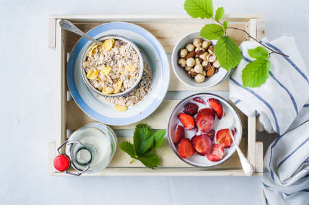 Muesli with fresh strawberries in a plate over a white concrete backgroundの写真素材