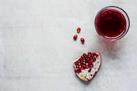 Red pomegranate and juice in a class on a grey concrete backgroundの写真素材