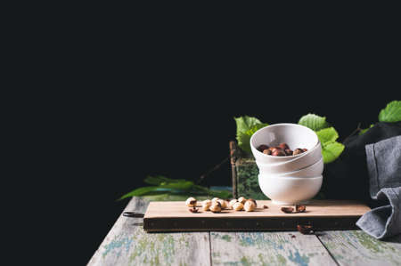 White cup with a filbert on a chopping board over a wooden tableの写真素材