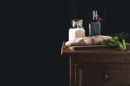 Homemade bread and ingredients for cooking on a kitchen table. Isolated on black backgroundの写真素材