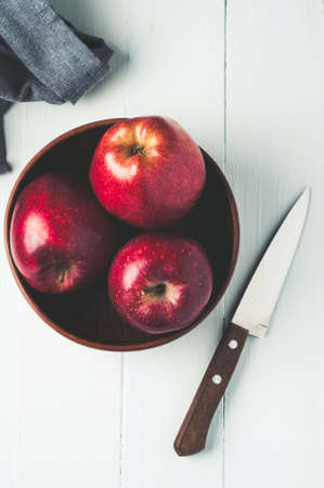 Red apples in a bowl on a light wooden background. Diet or healthy eating conceptの写真素材