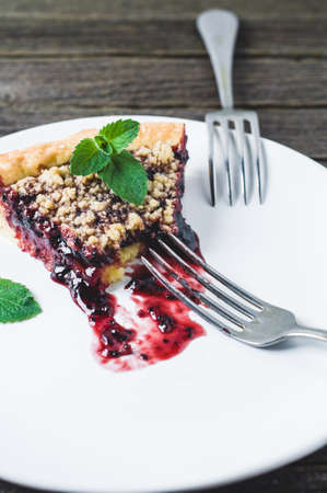 Portion of pie with jam on a white ceramic plate over a dark wooden backgroundの写真素材