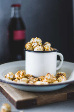 Popcorn in a white cup and drink in a bottle on a gray concrete backgroundの写真素材