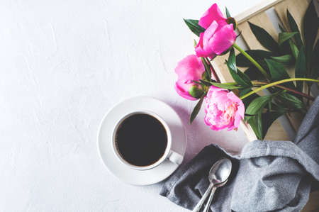 Pink peonies and  white cup of coffee  on a white concrete background. Breakfast or morning conceptの写真素材