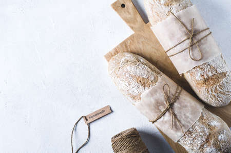 Homemade bread on a chopping board on a white concrete background
