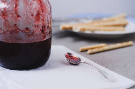 Homemade strawberry jam in jar and snacks on a grey concrete backgroundの写真素材
