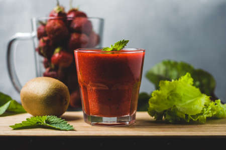 Fresh kiwi and strawberry juice in glass over wooden background. Diet, weight loss or healthy eating conceptの写真素材