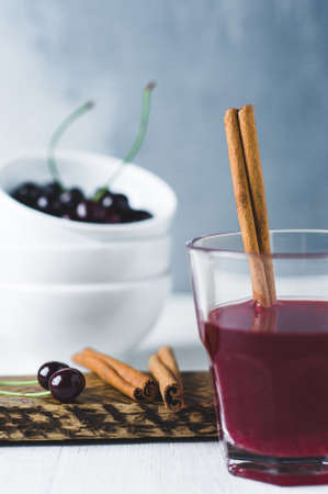 Fresh cherries in a white metal Cup and juice on white backgroundの写真素材