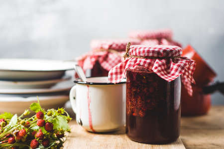 Homemade strawberry jam in jars and inredients on a wooden cutting boardの写真素材
