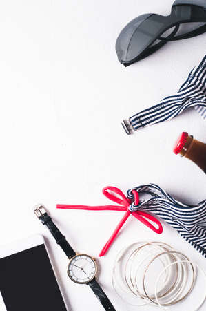 Retro style striped swimsuit and fashion accessories  on a white concrete background