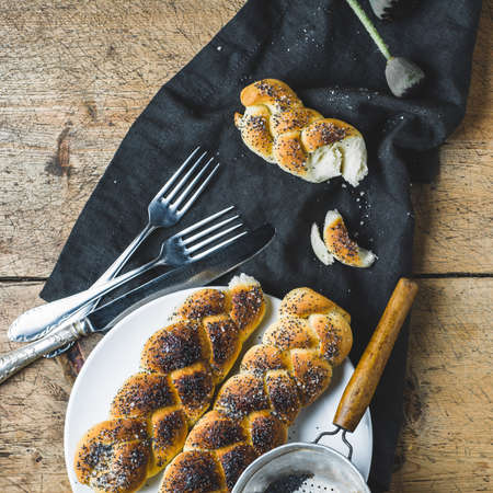 Homemade buns with poppy seeds on a white plate over old wooden tableの写真素材
