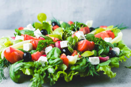 Fresh lettuce, tomatoes, olives and feta cheese in a bowlの写真素材