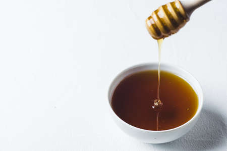 Fresh honey in a white cup on a white concrete backgroundの写真素材