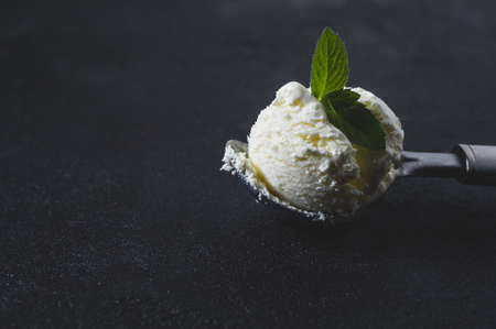 Homemade ice cream with mint in a spoon over black concrete backgroundの写真素材