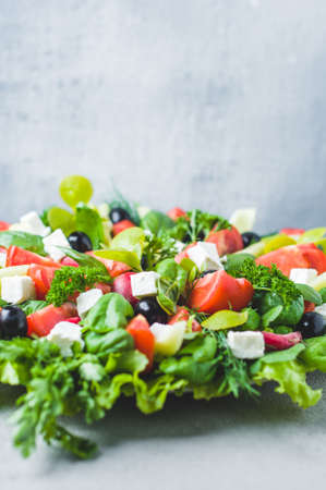 Fresh lettuce, tomatoes, olives and feta cheese in a bowlの写真素材