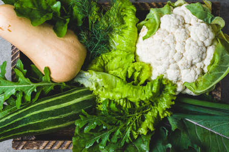 Vegetables in a wooden box on a gray concrete background
