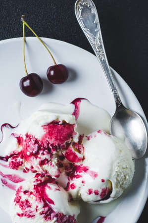 Homemade ice cream with sherry and berries on a plate over black concrete backgroundの写真素材