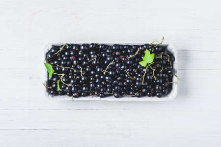 Black currant in a box over white wooden backgroundの写真素材